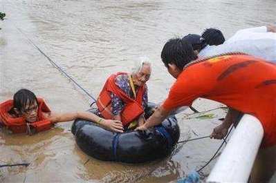 Fireman and members of a rescue group help an elderly woman out of the Jaro river near Iloilo city, central Philippines June 21, 2008. Typhoon Fengshen killed at least 17 people in floods and landslides in the Philippines and left a ferry adrift with over 700 passengers and crew on Saturday. REUTERS/Stringer [From BuhaysaKorea.com]
